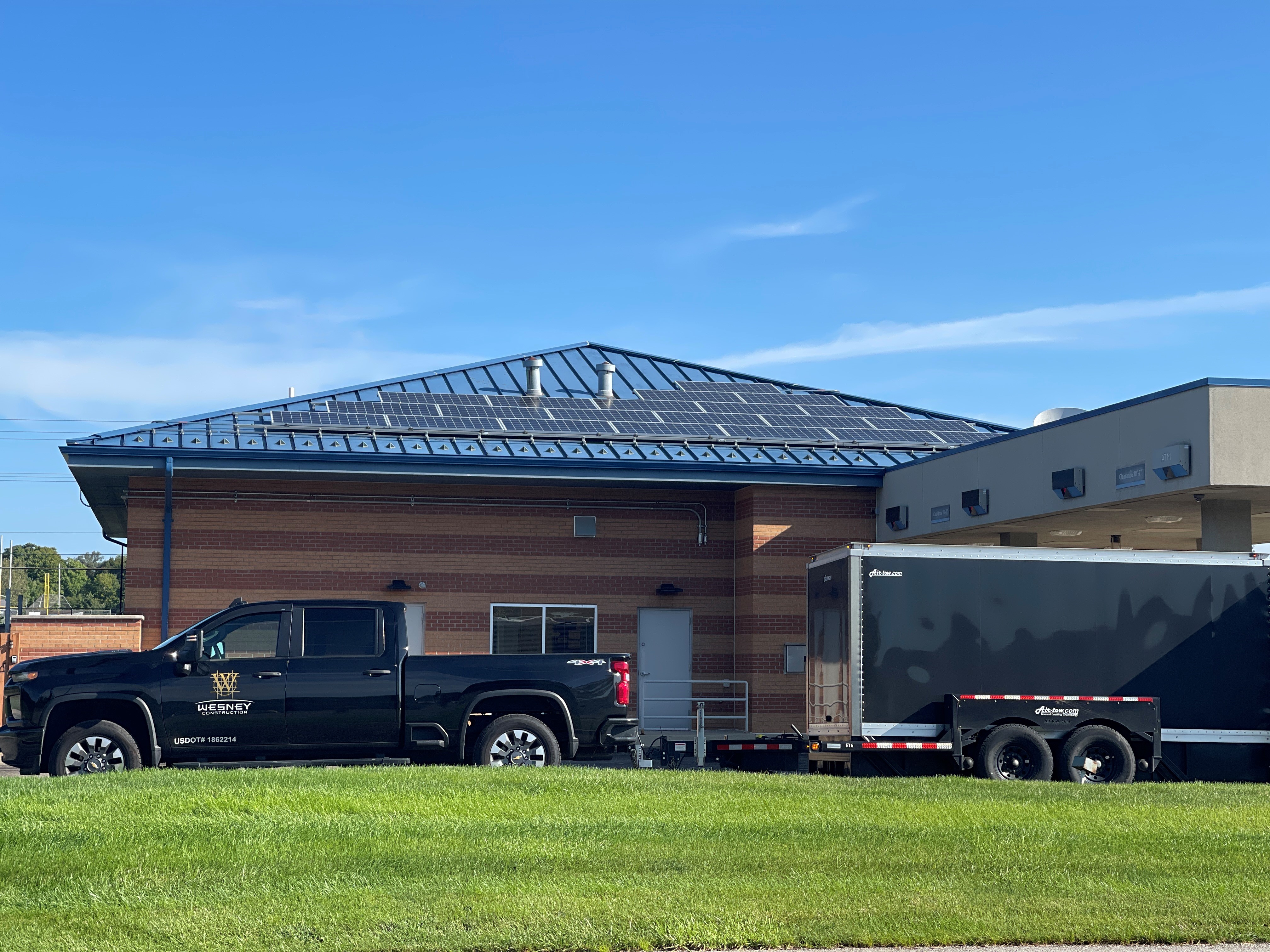 Wesney Construction service truck and enclosed equipment trailer staged outside an occupied commercial building during an active remodel.